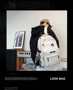 Detail view of white high-capacity backpack with KDMILD logo and multiple zipper pockets