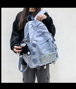 Detail of light blue nylon backpack featuring cross cord design and breathable mesh pocket