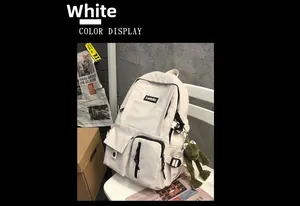 Detailed view of white canvas backpack featuring front pockets and a green frog keychain