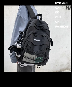Detail of black nylon backpack featuring crisscross rope design and plush monkey keychain