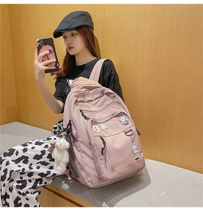 Detailed side view of pink nylon school backpack with cute bear pendant and badges