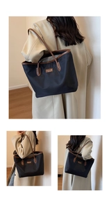 Detail of a black nylon tote bag with brown leather handles and brand logo tag