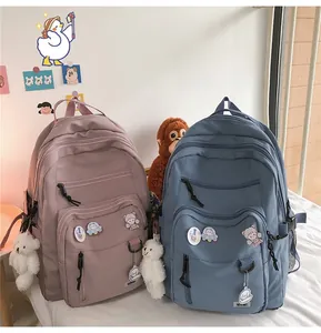 Detail of pink and blue school backpacks with plush bear pendants and cute badges