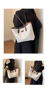 Detail of a large cream tote bag with brown leather trim and slim shoulder handles
