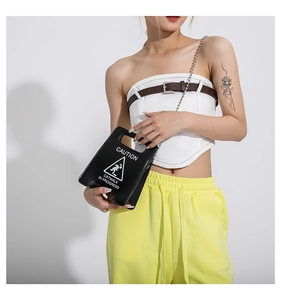 Détail du sac à main noir en forme de panneau avec chaîne à perles et texte imprimé