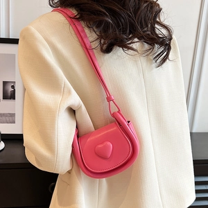 Pink heart-shaped mini crossbody bag for girls with adjustable strap worn on casual suit