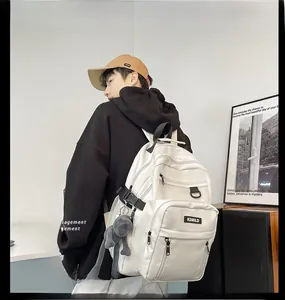 Model wearing a white large capacity backpack with multiple layers and plush pendant