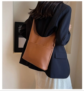 Detail of caramel brown pebbled leather hobo bag with front pocket on model