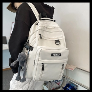 Detail of white multi-layer backpack featuring side pockets and a cute plush animal charm