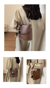 Detail of a brown leather bucket bag with woven handle and a cute rabbit doll pendant