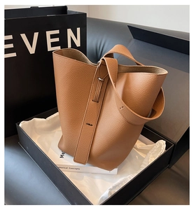 Détail du sac seau en cuir marron avec motif litchi dans un coffret cadeau premium