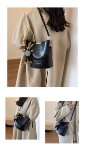 Detail of black textured bucket bag with woven chain and cute rabbit charm pendant