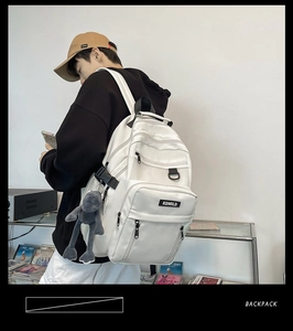 Detailed side view of a large white multi-layer backpack with a plush charm on straps