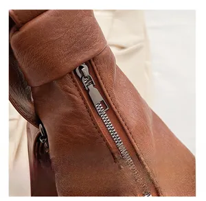 Detail of smooth metal zipper and textured brown leather on large tote bag