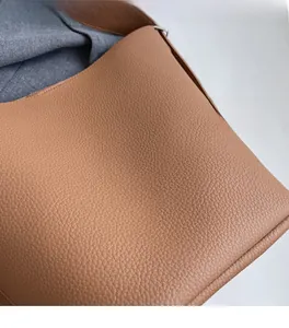 Détail rapproché de la texture du cuir litchi marron sur un sac seau élégant
