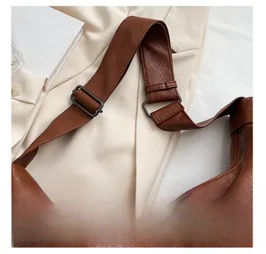Detail view of brown pebbled leather shoulder strap with adjustable square metal buckle