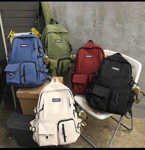 Five minimalist canvas backpacks in various colors with multi-pocket utility design