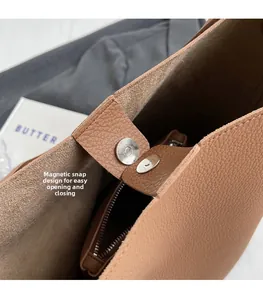 Détail de la fermeture magnétique et de la poche intérieure zippée dans un sac en cuir brun