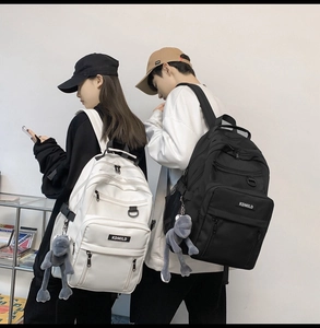 Close-up of minimalist black and white backpacks with plush frog pendant details