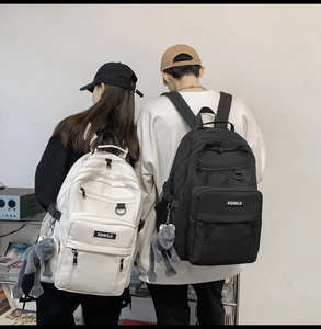 Detail of minimalist black and beige nylon backpacks with multiple pockets and cute charms