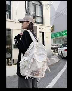 Detail of off-white backpack showing mesh pocket and adjustable cross-rope design