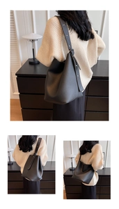 Détail du sac seau noir en cuir grainé avec une large bandoulière réglable pratique