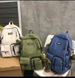 Three colors of student backpacks with multi-pocket design and plush frog pendant