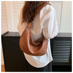 Close-up of a brown leather shoulder bag with decorative knot details on a model
