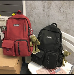 Detailed view of red and black students backpacks with brand logo and cute frog pendants