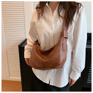 Detail of a dark brown crescent tote bag with knot shoulder strap on female model