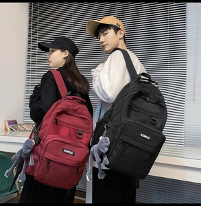 Detail of red and black high-capacity backpacks with multi-layer pockets and plush charm