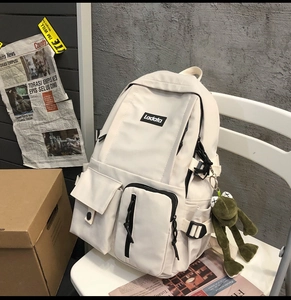 Close-up of the multi-pocket cream student backpack with Ladata logo and frog pendant