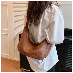 Detail view of caramel brown hobo shoulder bag with litchi texture on a model