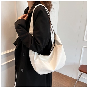 White minimalist half-moon tote bag with pebbled texture and wide shoulder strap