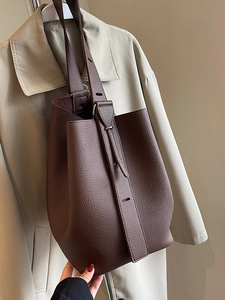 Sac seau classique en cuir grainé marron foncé avec bandoulière réglable sur trench