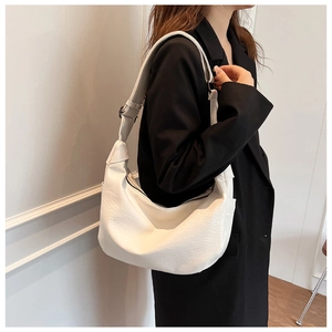Close-up of white crescent shoulder bag with soft PU leather texture and adjustable strap