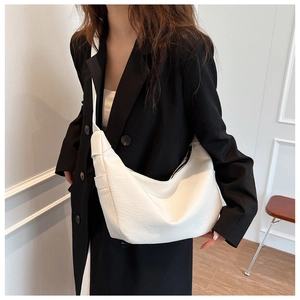 Detail of white crescent shoulder bag with textured faux leather and wide strap