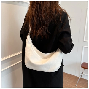 Detail of white pleated hobo bag with wide shoulder strap showing texture and size