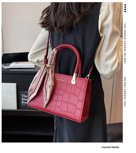 Detail of red crocodile texture tote with woven handle and elegant silk scarf accessory