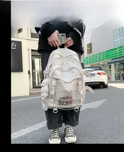 Detail of a creamy white nylon backpack with mesh pockets, elastic cords and a plush bear