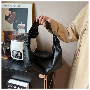 Detail of black pebbled leather crescent hobo bag featuring a decorative shoulder knot