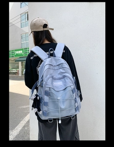 Street style shot of a blue student backpack featuring cross elastic ropes and a plush monkey