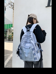 Outdoor lifestyle view of a light blue student backpack with rope detail and plush charm