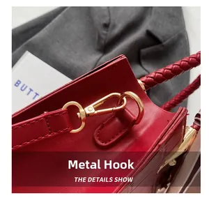 Detail of red crocodile texture handbag featuring golden hardware hook and woven handle