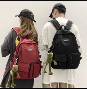 Detailed view of large capacity school backpack with frog charm in red and black colors