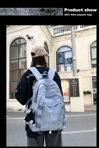 Outdoor back view of a light blue nylon backpack with mesh pockets and rope details