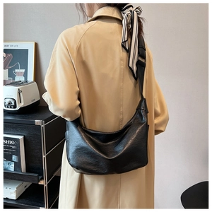 Fashionable black leather hobo bag worn by model in a casual lifestyle setting