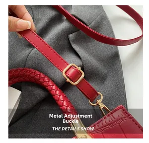 Close-up of red crocodile pattern bag featuring gold metal buckles and woven handle