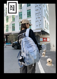 Detail view of ice blue backpack featuring adjustable buckles and a plush monkey charm