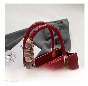 Close-up of red crocodile-pattern tote bag with woven handles and silk scarf detail